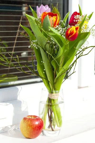 Spring bouquet with tulips and an apple — Stock Photo, Image