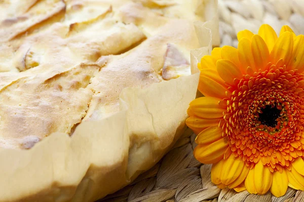 Apfelkuchen und eine Blume auf einer Weidenmatte — Stockfoto