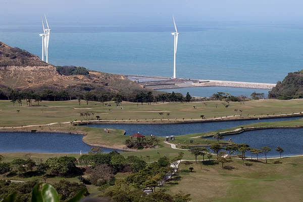 Lugar de golf con agradable verde y molino de viento de energía después del lugar — Foto de Stock