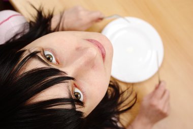 Beautiful girl with by empty plate at the table clipart