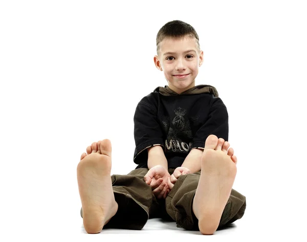 Liten pojke sitter barfota, isolerade på vit — Stockfoto