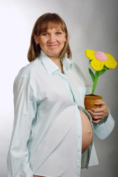 Маленька вагітна жінка з квітковим горщиком — стокове фото