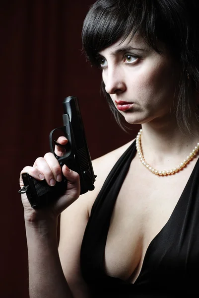 Vrouw in avondjurk houdt pistool — Stockfoto