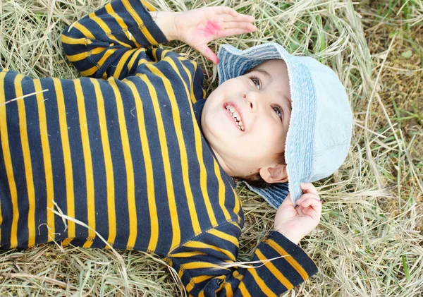 Игривый мальчик лежит на сене — стоковое фото