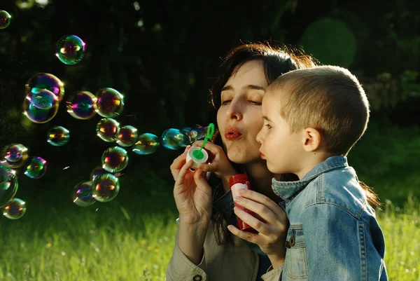 Moeder en zoon maken zeepbellen buitenshuis — Stockfoto