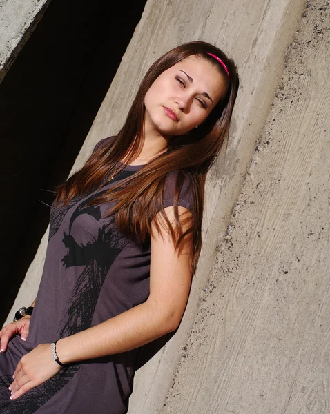 Young beautiful woman lean by the concrete wall — Stock Photo, Image