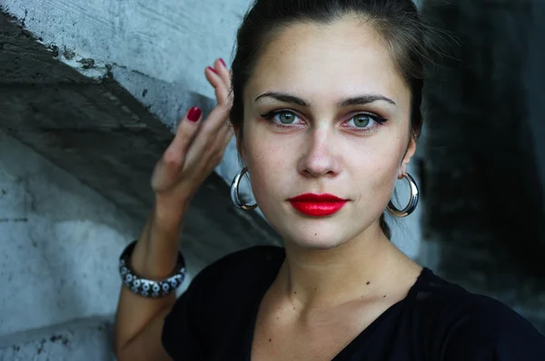 Ritratto della ragazza con gli occhi verdi vicino al muro di cemento — Foto Stock