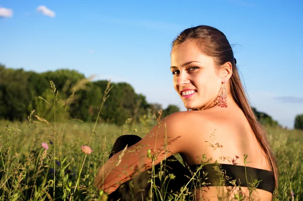 Девушка наслаждается летом, сидя на лугу — стоковое фото