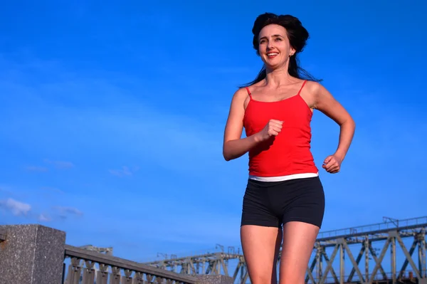 Donna che fa jogging su sfondo uban cielo blu — Foto Stock