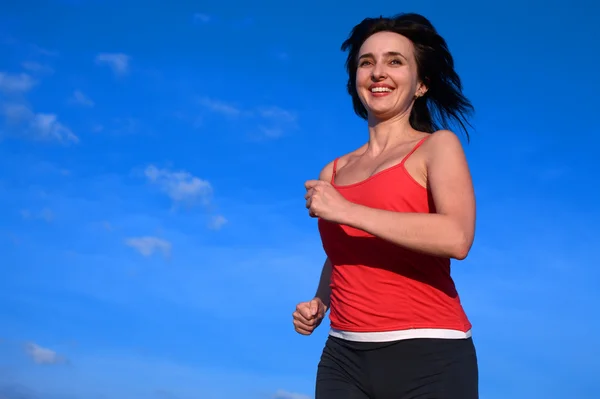 Femme jogging sur le fond bleu ciel — Photo