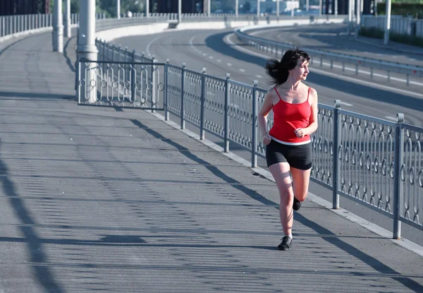 Vrouw joggen op lege snelweg — Stockfoto