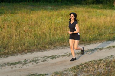 Woman jogging outdoors in forest road clipart