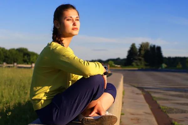 Porträt des Mädchens, das an der Grenze in der Abendsonne sitzt — Stockfoto