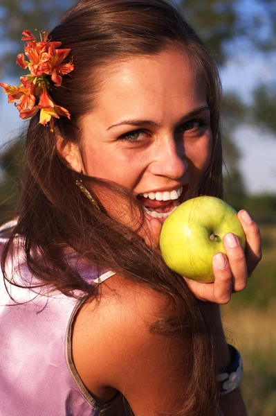 Woman with apple with flower in hair — Stock Photo, Image