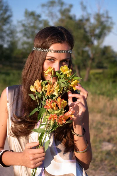 Hippie girl smells lily outdoors — Stock Photo, Image