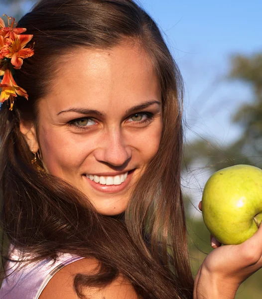 Frau mit Apfel mit Blume im Haar — Stockfoto