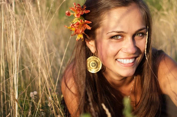 Hermosa chica con flor en el pelo en la hierba —  Fotos de Stock