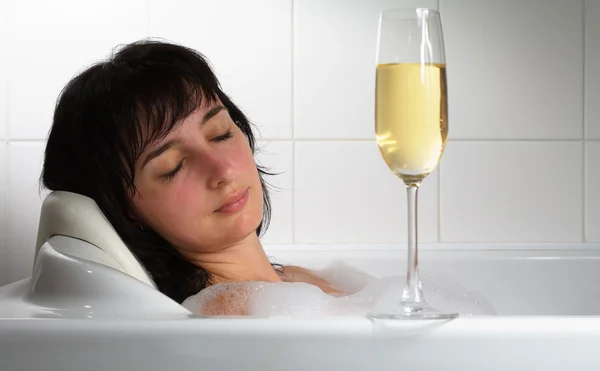 Mulher dormindo em banho com copo de champanhe — Fotografia de Stock