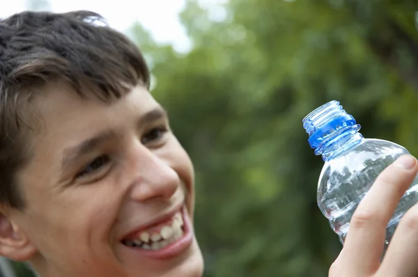 Sonrisa suave del niño y la botella azul — Foto de Stock