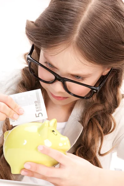 Menina com banco porquinho e dinheiro — Fotografia de Stock