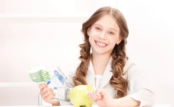 Little girl with piggy bank and money — Stock Photo, Image
