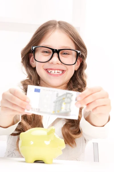 Meisje met piggy bank en geld — Stockfoto