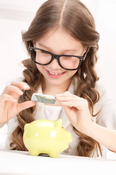 Liten flicka med spargris och pengar — Stockfoto