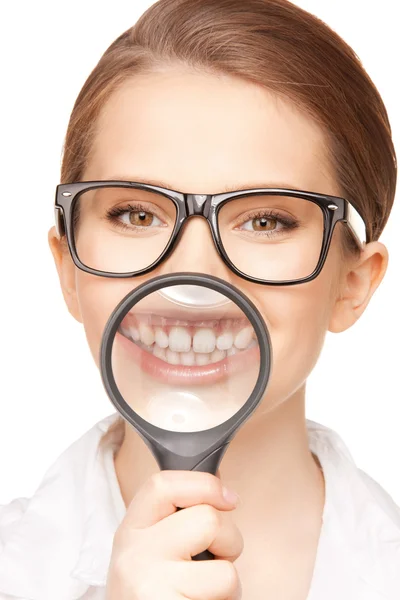Woman with magnifying glass showing teeth — Stock Photo, Image