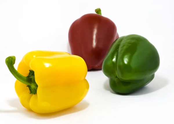 Tři barevné papriky na bílém pozadí — Stock fotografie