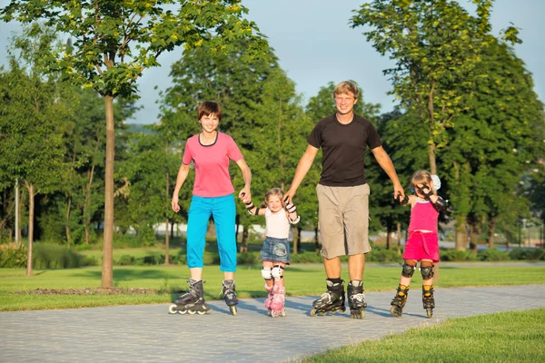 Родители и две дочери катаются на коньках — стоковое фото