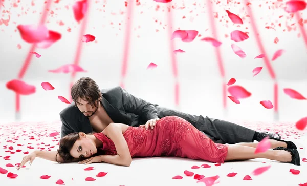 Atractiva pareja sobre la caída de pétalos de rosa — Foto de Stock