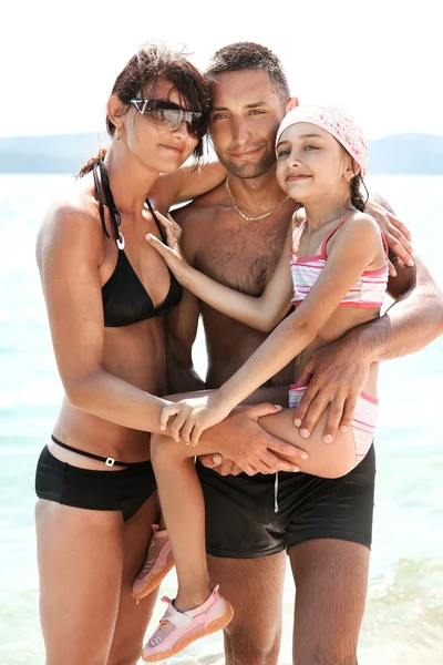 Young family embracing on a sandy beach — Stock Photo, Image