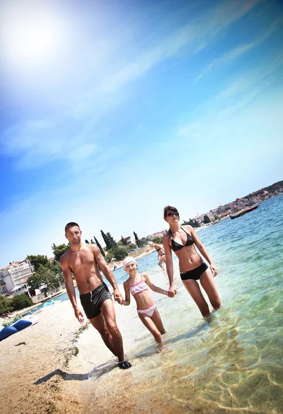 Jeune famille marchant sur une plage — Photo