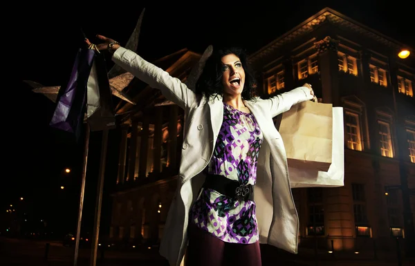 Радостная леди с сумками для покупок, ночью — стоковое фото