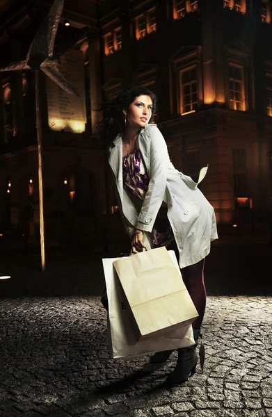 Senhora alegre segurando sacos de compras, na noite — Fotografia de Stock