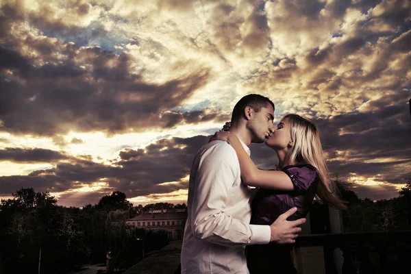 Schönes Paar, das sich bei bewölktem Sonnenuntergang umarmt — Stockfoto