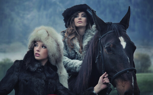 Two sensual female beauties posing with a horse