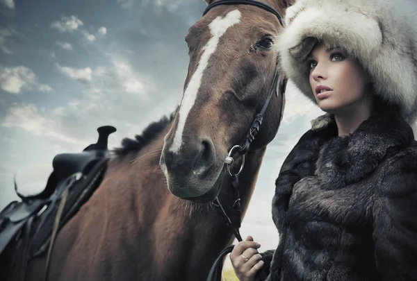 Nostalgic young brunette posing next to a horse — Stock Photo, Image
