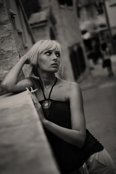 古い都市の通りのバック グラウンドで若い女性の喫煙タバコの肖像画 — ストック写真