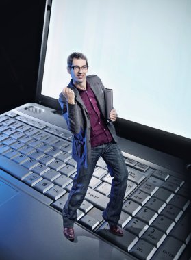 Conceptual photo of a happy man standing on the laptop's keyboar clipart