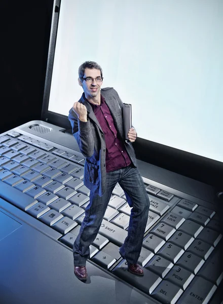 Концептуальное фото счастливого человека, стоящего на клавиатуре ноутбука — стоковое фото