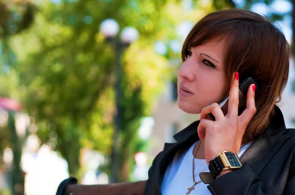 stock image The young girl speaks by phone in park