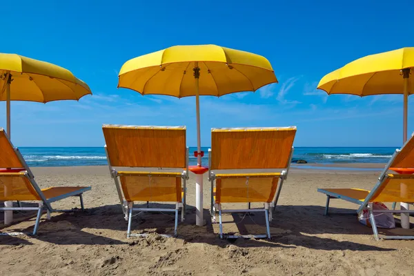 Lounge chairs under a yellow umbrella — Stock Photo, Image