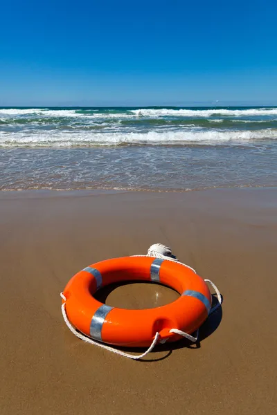 Bóia de salvação vermelha deitada na areia na praia — Fotografia de Stock
