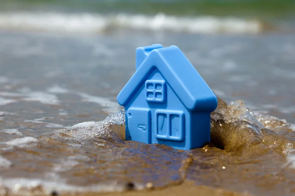 Spielzeug-Plastikhaus auf dem Sand spült Welle — Stockfoto