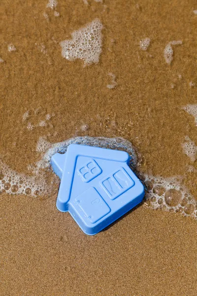 Пластиковий іграшковий будинок лежить на піску — стокове фото