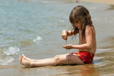 küçük kız dalgalar bir plajda otururken