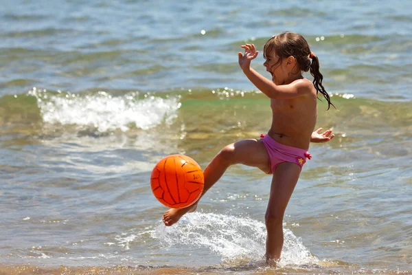 Маленькая девочка на пляже ударила по мячу — стоковое фото