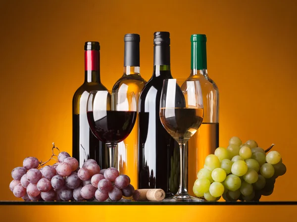 Пляшки, келихи та виноград — стокове фото