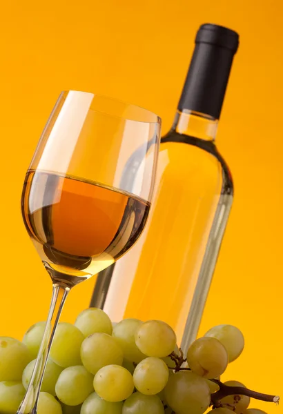 Нижний вид на стакан бутылки белого вина и винограда — стоковое фото